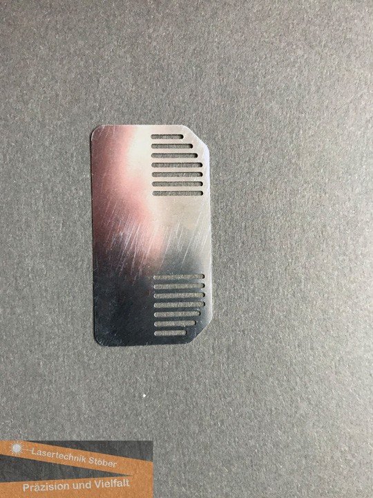 Dünnes Metallblech mit gelaserten Lüftungsschlitzen und abgerundeten Kanten – Beispiel für technische Feinlaserteile