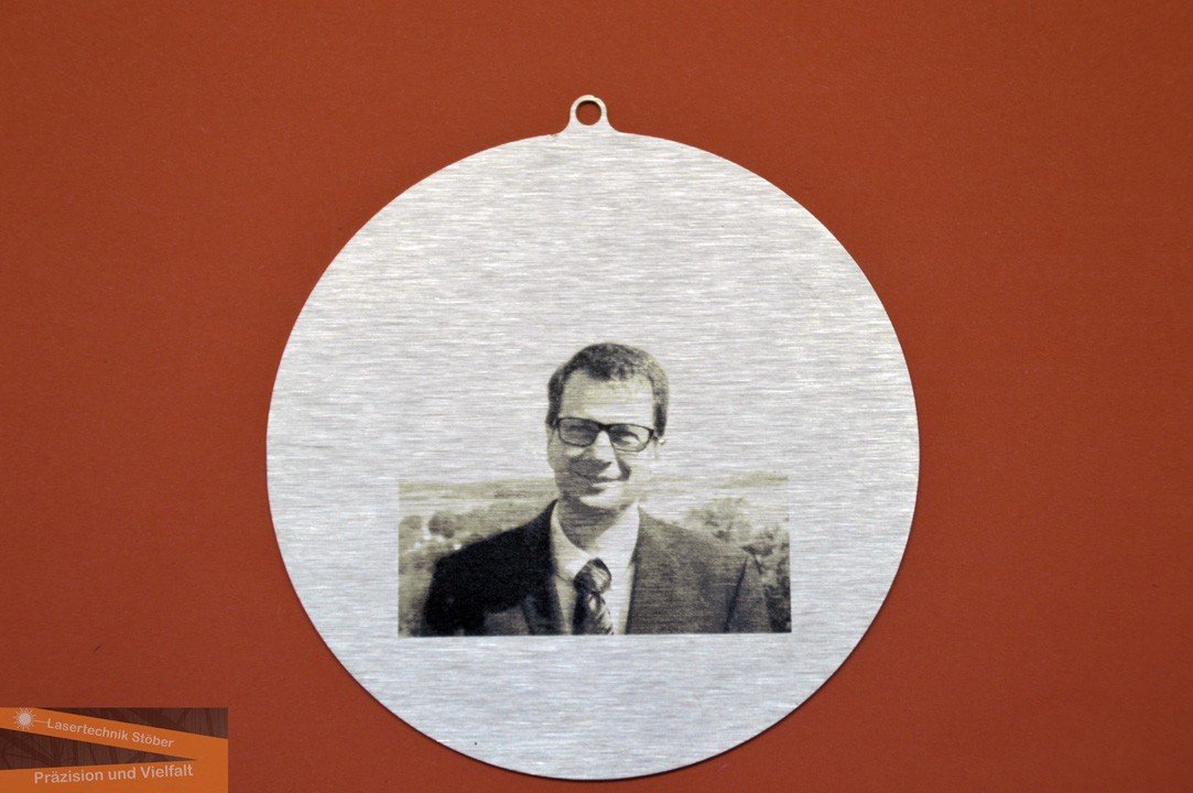 Portrait eines Mannes als Lasergravur auf runder Aluminiumscheibe mit Aufhänger – Beispiel für Gravurtechnik auf Metall