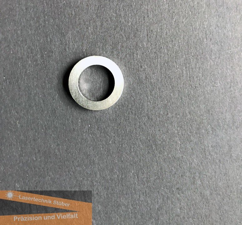 Rundes Flachteil aus Metall mit sauberem Laserschnitt auf dunklem Hintergrund – Beispiel für Präzisionslaserschneiden