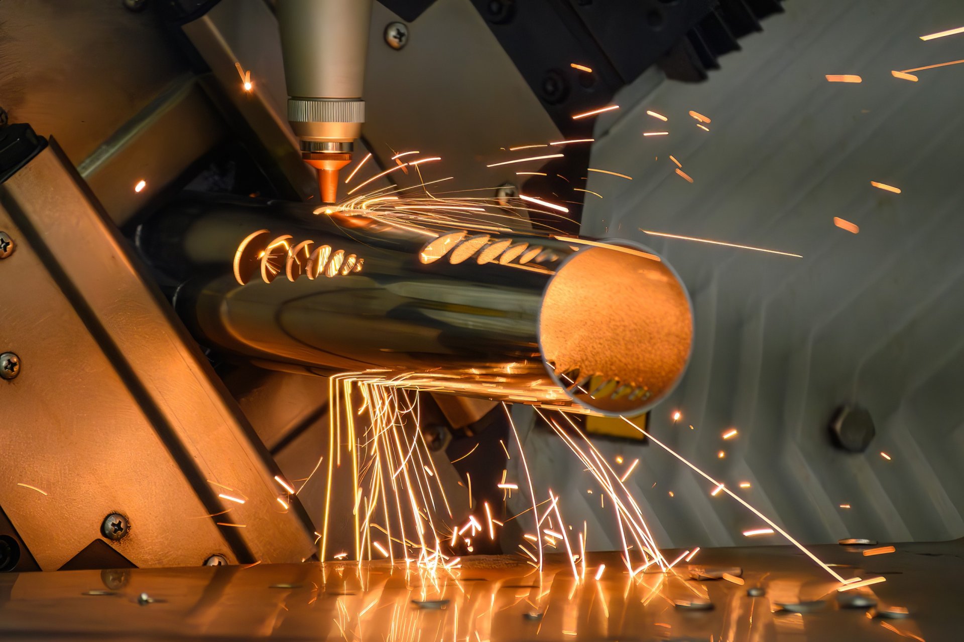 Laserstrahl schneidet rundes Metallrohr, helle Funken fliegen in alle Richtungen