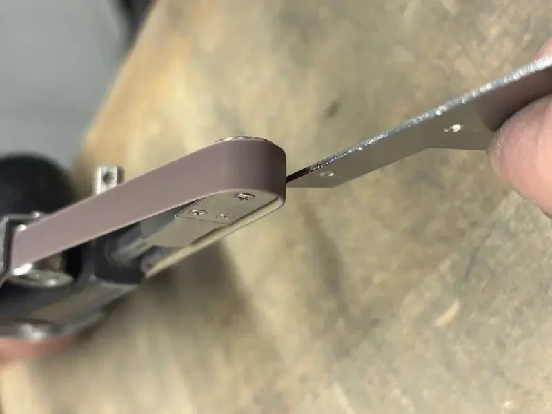 Entfernen von Mikrostegen an einem Laserteil mit einer handgeführten Bandschleifmaschine